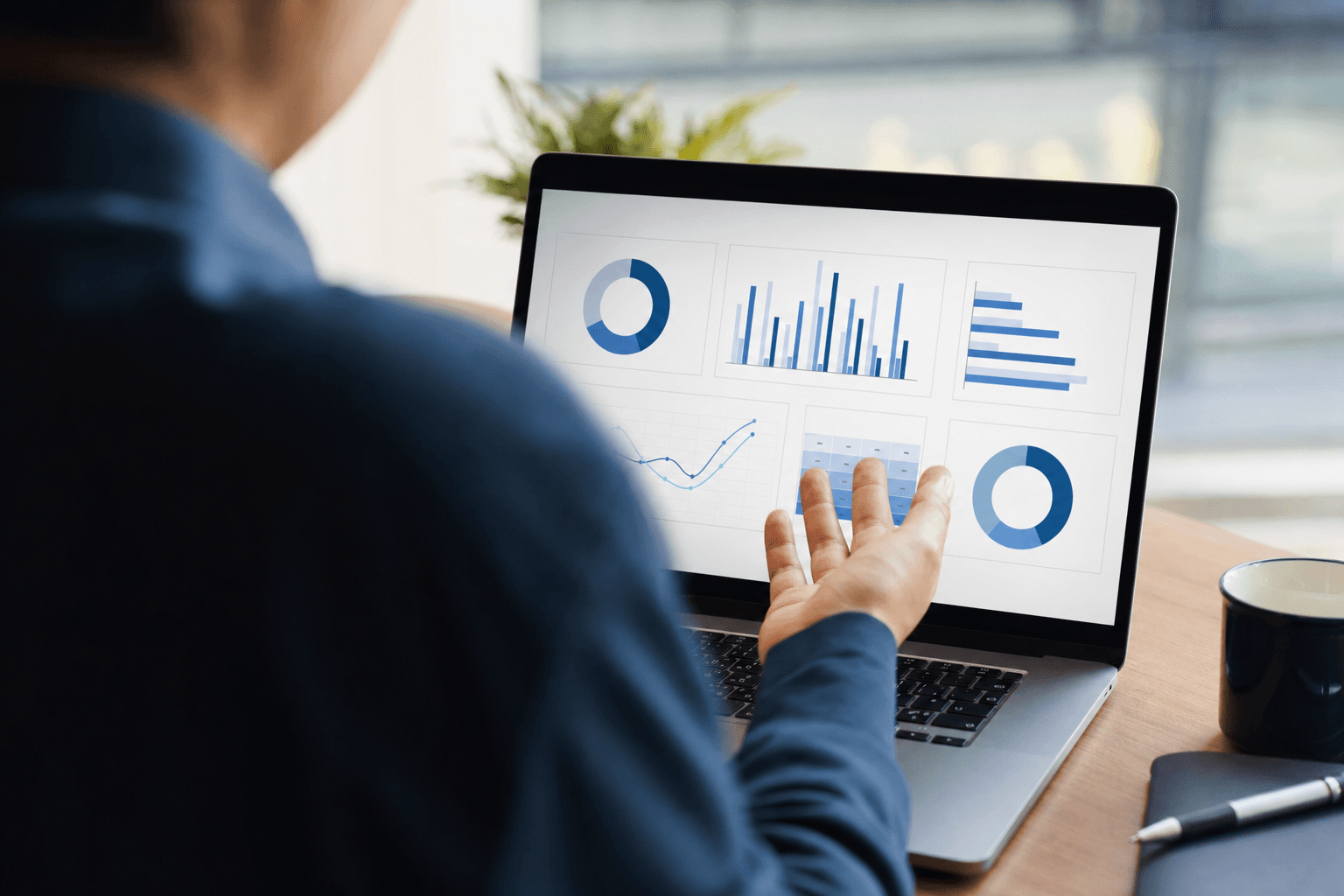 A person reviewing a business analytics dashboard on a laptop, viewed over the shoulder